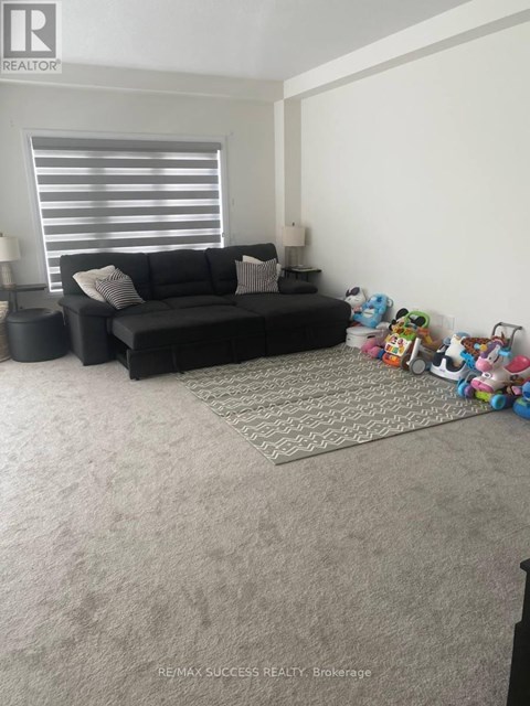 A living room with a black couch and a rug.