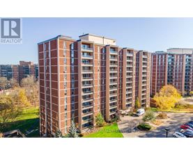 A tall apartment building with a parking lot in front.