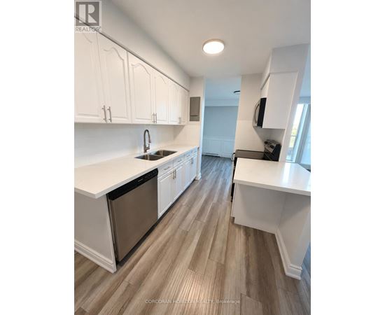 A kitchen with white cabinets and a wooden floor.