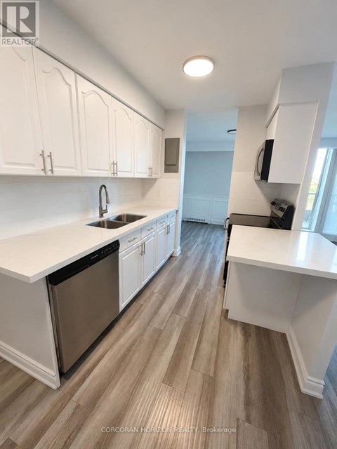 A kitchen with white cabinets and a wooden floor.