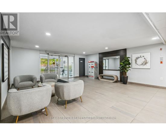 A modern living room with grey armchairs and a wooden floor.
