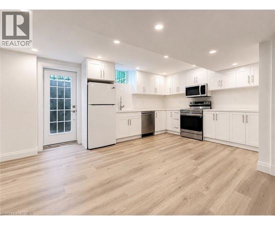A spacious kitchen with white cabinets and a wooden floor.