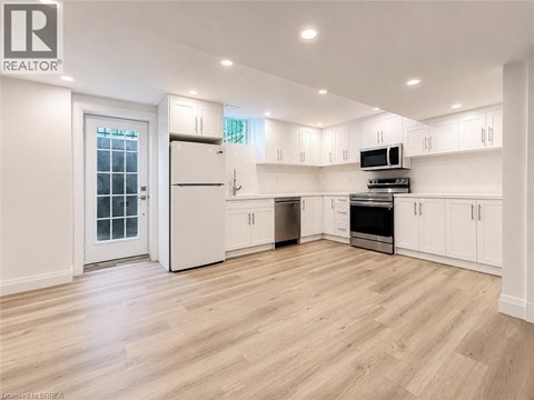 A spacious kitchen with white cabinets and a wooden floor.