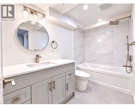 A bathroom with a marble wall and a round mirror above a sink.