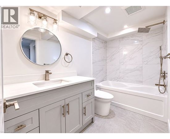 A bathroom with a marble wall and a round mirror above a sink.