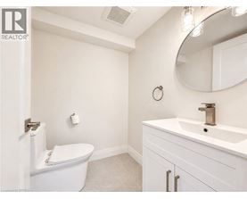 A white bathroom with a toilet, sink, and mirror.