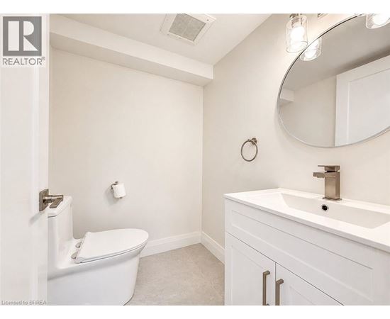 A white bathroom with a toilet, sink, and mirror.