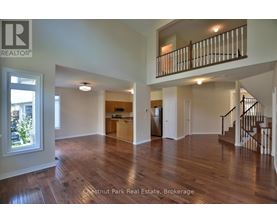 A spacious living room with hardwood floors and a staircase leading to the upper level.
