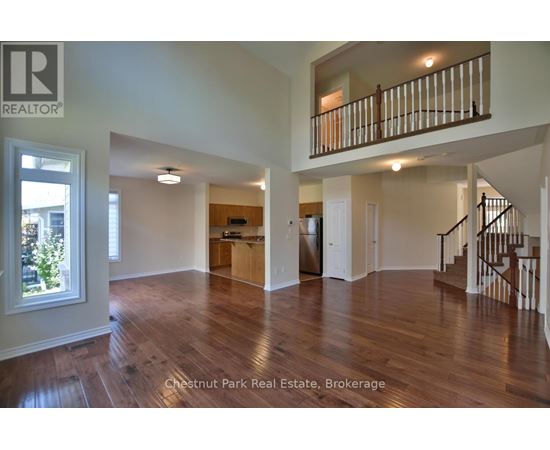 A spacious living room with hardwood floors and a staircase leading to the upper level.