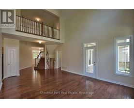 A spacious room with wood flooring and a staircase leading to another level.
