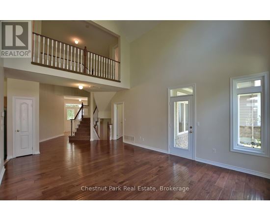 A spacious room with wood flooring and a staircase leading to another level.