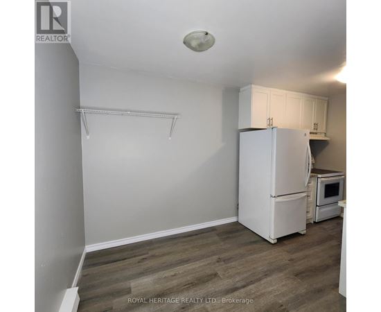 A white refrigerator in a kitchen with wooden flooring.