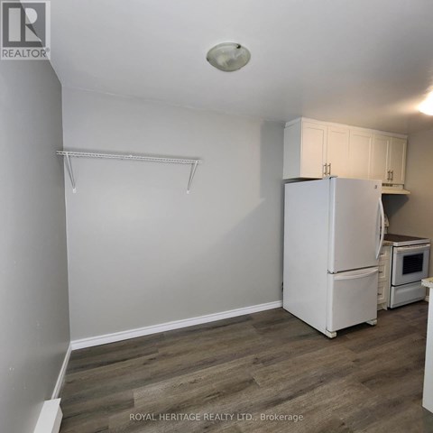 A white refrigerator in a kitchen with wooden flooring.