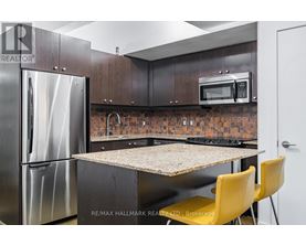 A kitchen with a refrigerator, microwave, and a table with yellow chairs.