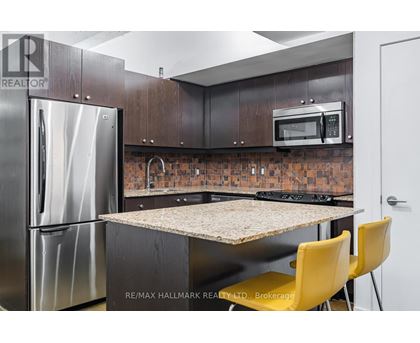A kitchen with a refrigerator, microwave, and a table with yellow chairs.