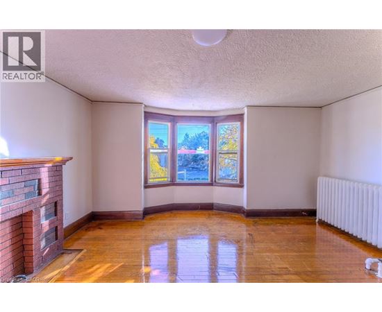 A room with a fireplace and a window with a view of trees.