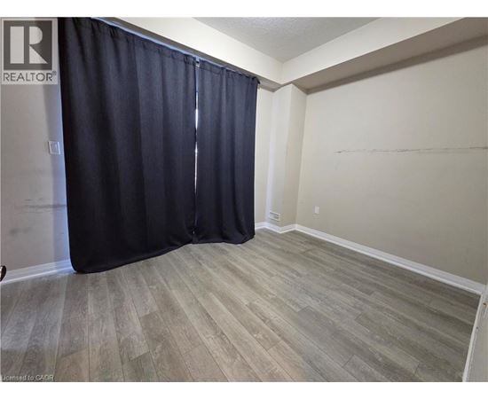 A room with a black curtain and wooden flooring.