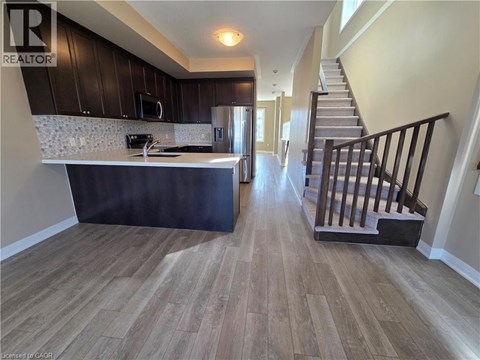 A kitchen with a stove top oven and a staircase.