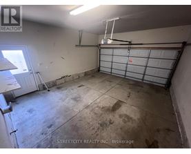 A garage with a white wall and a closed grey garage door.
