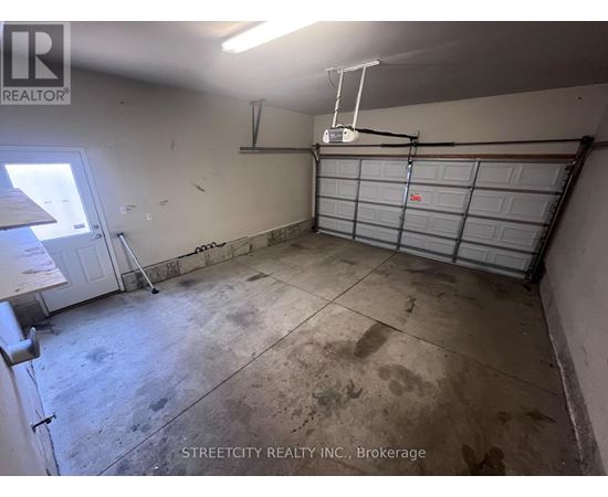 A garage with a white wall and a closed grey garage door.