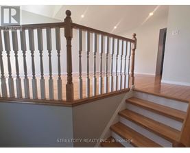 A staircase with a wooden handrail and white balusters.