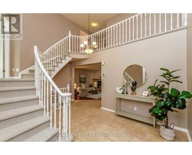 A staircase with a white railing leads to a living room.