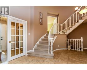 A staircase with a white railing and beige carpeted steps leads to a second floor.