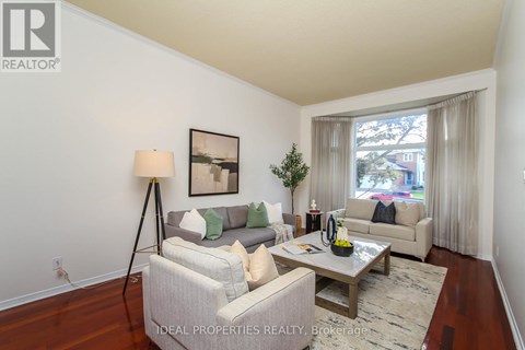 A well-lit living room with a grey couch and a wooden floor.