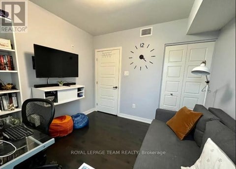 A living room with a grey couch and a black television.