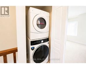 A white washing machine is stacked on top of another white washing machine in a small space.