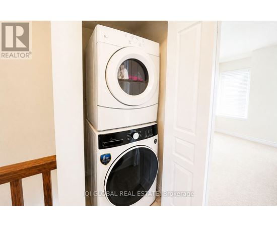 A white washing machine is stacked on top of another white washing machine in a small space.