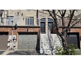 A house with a grey garage door and a tree in front.