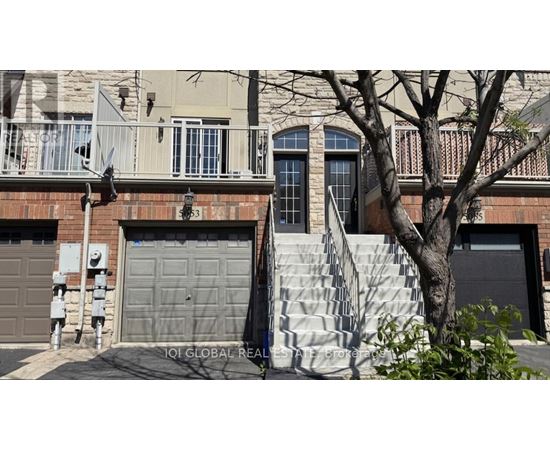 A house with a grey garage door and a tree in front.
