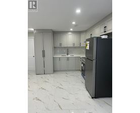 A kitchen with a black fridge and marble flooring.