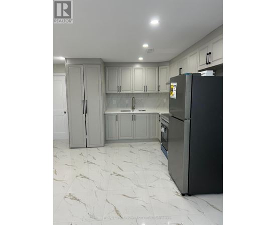 A kitchen with a black fridge and marble flooring.