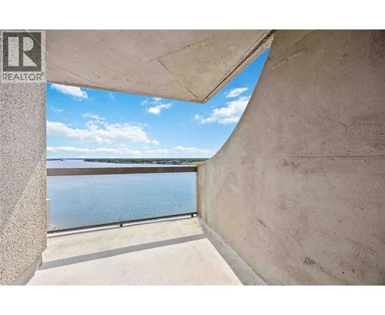 A view from a window looking out to a pool and a body of water.