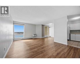 A spacious room with wooden flooring and a large window overlooking the beach.