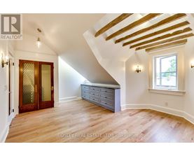 A room with wooden floors and a window with a view of trees.