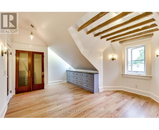 A room with wooden floors and a window with a view of trees.