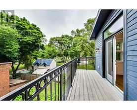 A balcony with a black railing overlooks a lush green yard.