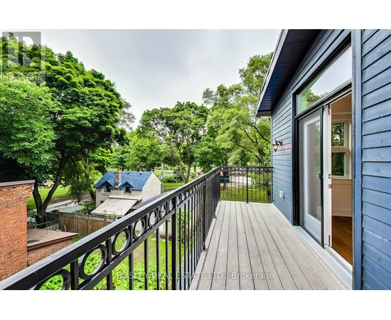 A balcony with a black railing overlooks a lush green yard.