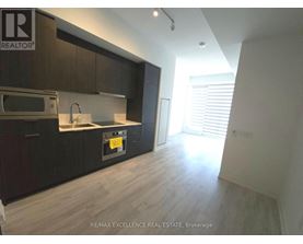 A kitchen with dark wood cabinets and a microwave above the stove.