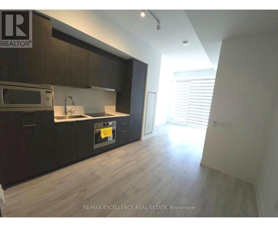 A kitchen with dark wood cabinets and a microwave above the stove.