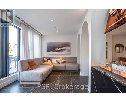 A modern living room with a grey sofa and a large painting on the wall.