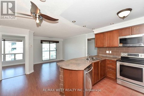 A kitchen with wooden cabinets and a fan on the ceiling.