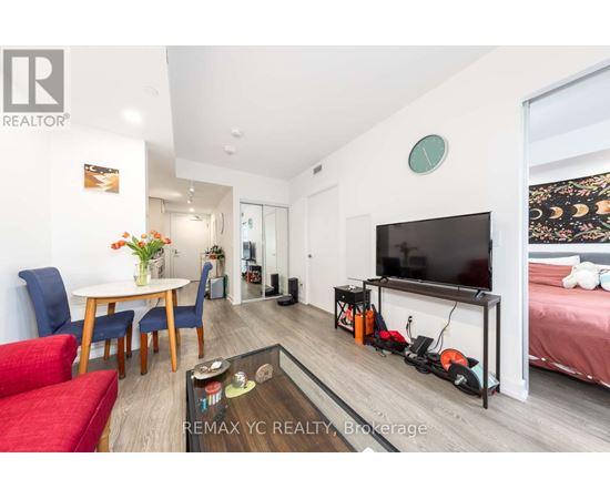 A living room with a red couch, a white table, a flat screen TV, and a glass coffee table.