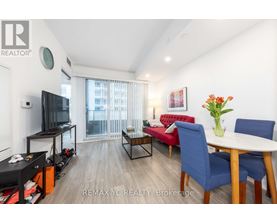 A living room with a red sofa, a blue chair, a white table, and a television.