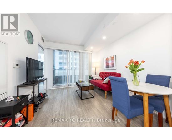 A living room with a red sofa, a blue chair, a white table, and a television.