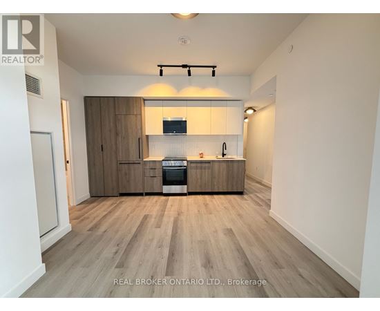 A kitchen with wooden floors and cabinets, and a stove top oven.