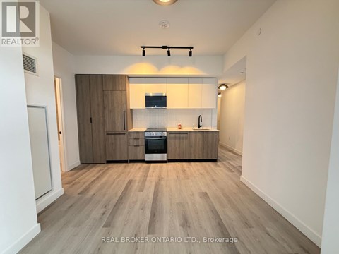 A kitchen with wooden floors and cabinets, and a stove top oven.